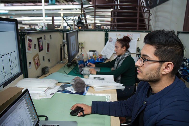 Two students working at their space in the design studio