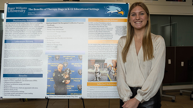 Senior Ashlyn Finn with her poster about therapy dogs helping in classrooms.