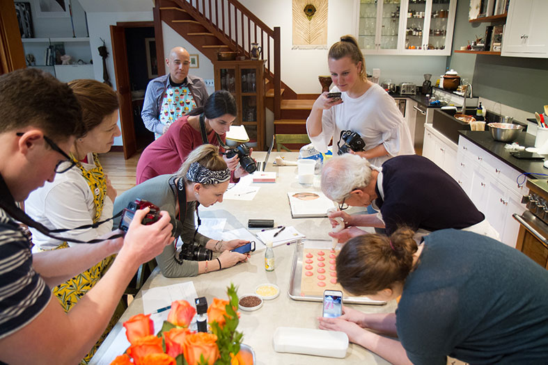 Students take photos and video of Schuhmacher placing the cookie mix on a sheet pan.