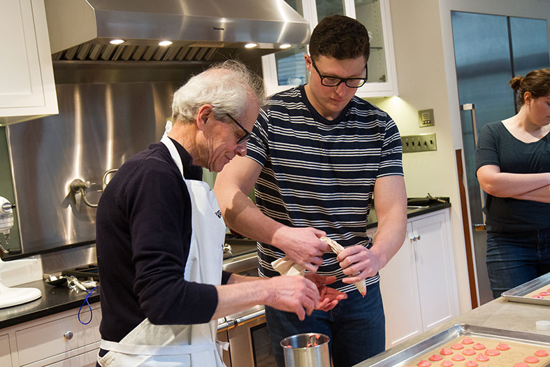 Schuhmacher explains to senior Josh Rosenberg how to properly hold the pastry bag.