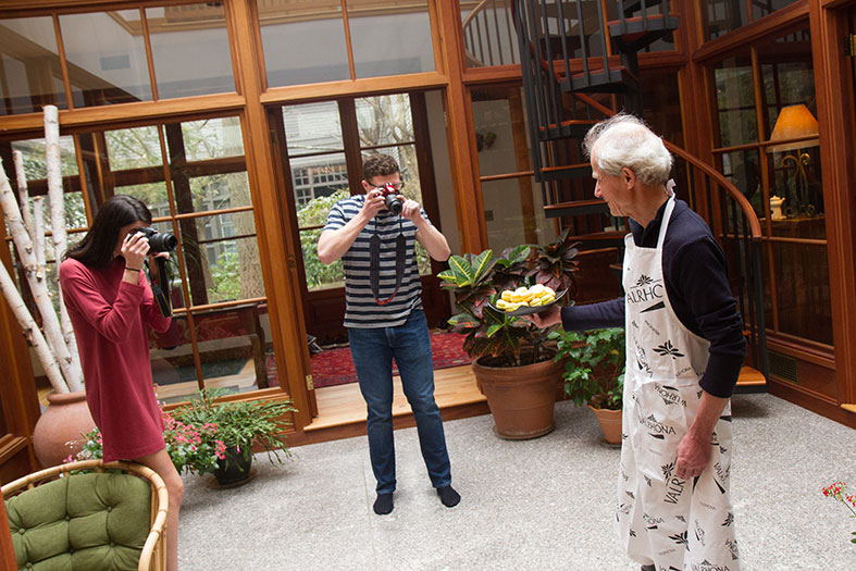 Natalie MacPhee and Josh Rosenberg take photos of Schuchmacher with a plate of macarons.