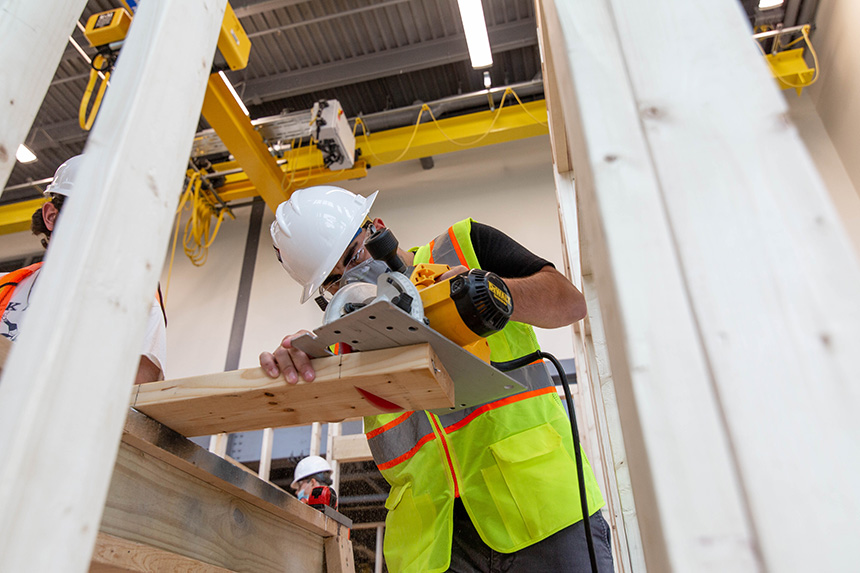 A Construction Management student cutting a piece of wood