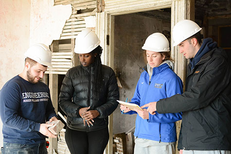 Students inspect their notes in a building they are renovating