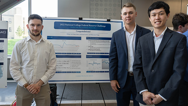 Three Economic students standing with their poster at SASH 