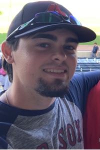 Student wearing a red sox hat and shirt at a baseball game