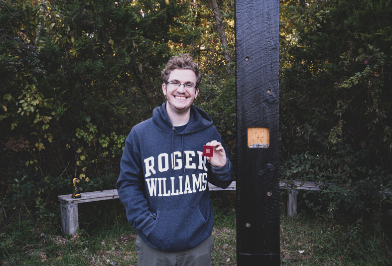 Student holding QR cod next to pillar. 