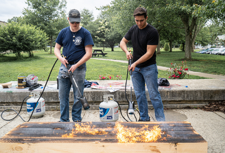 Two students charring wood. 