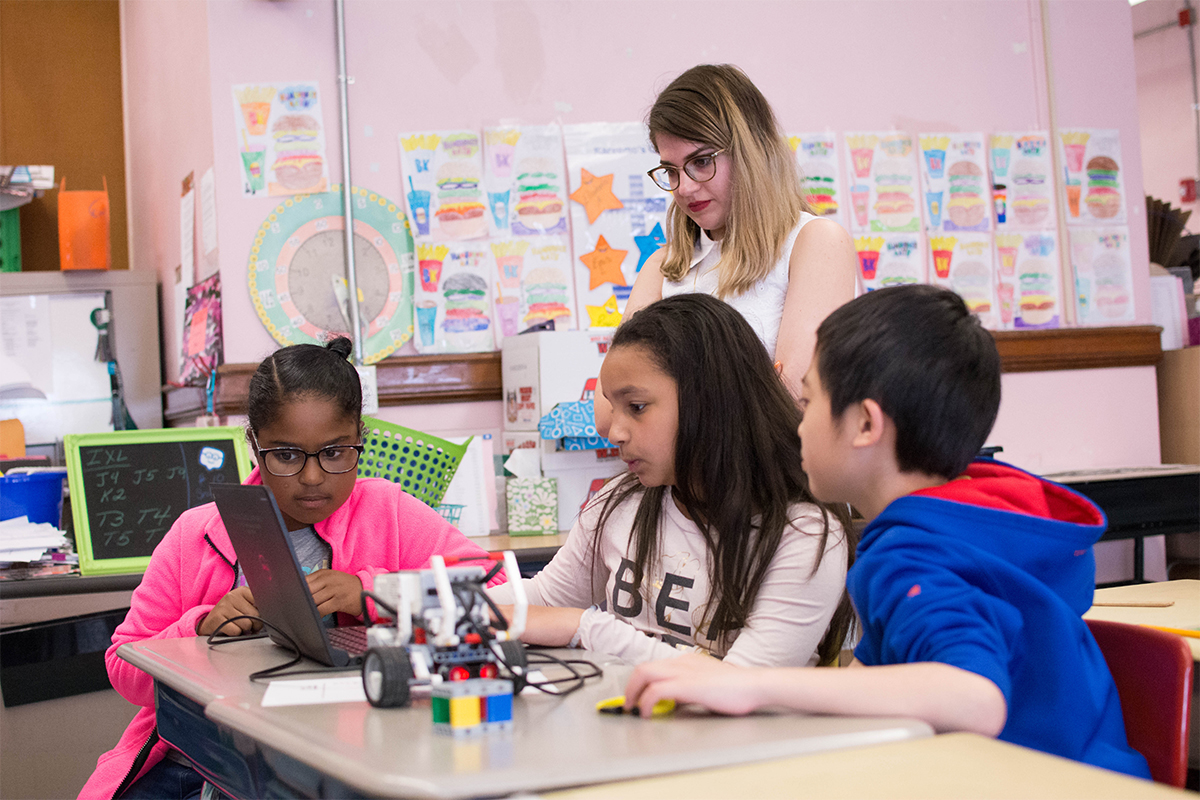 RWU student watchesstudents adjust their programing code-block