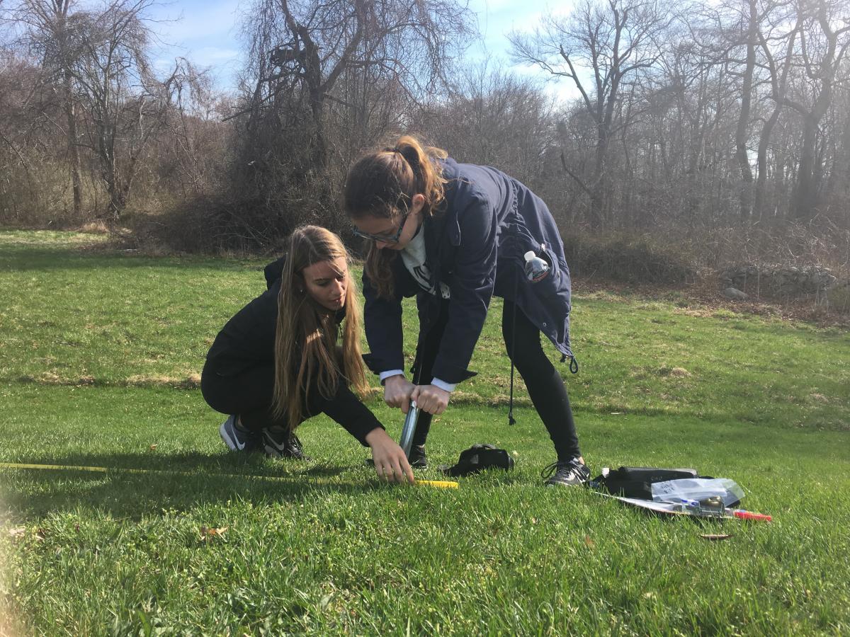 Students mark a spot on the ground.