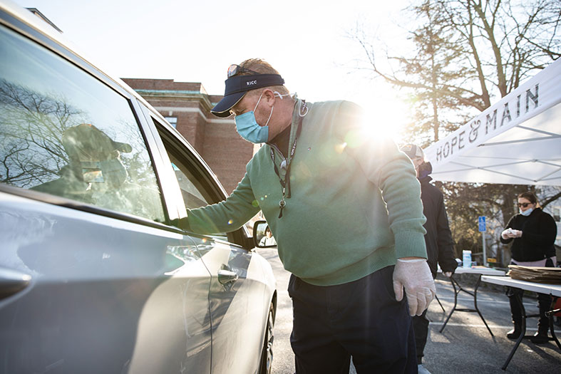 RWU dining staff member helps distribute food to community members.