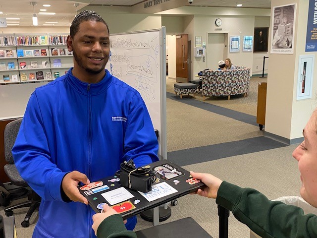 IT staff member passing laptop to an RWU student