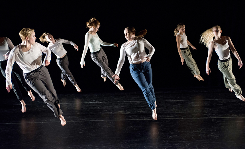 Seven students jump in a group performance