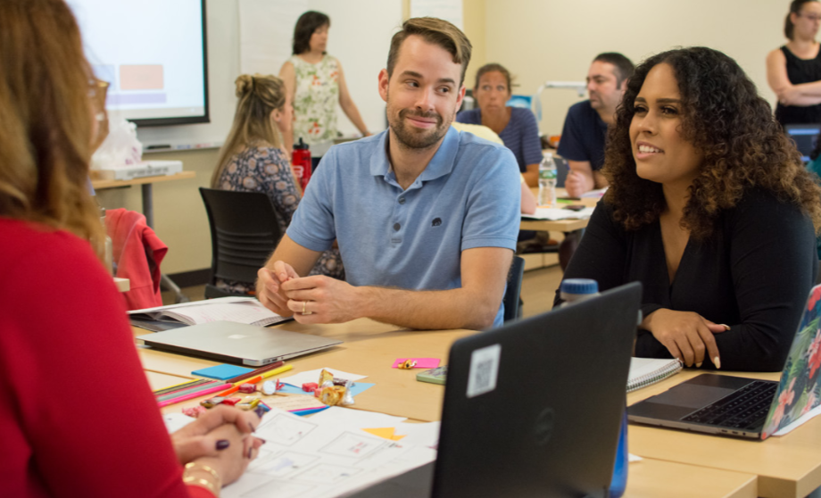 image of University College students in conversation, seated at a table 