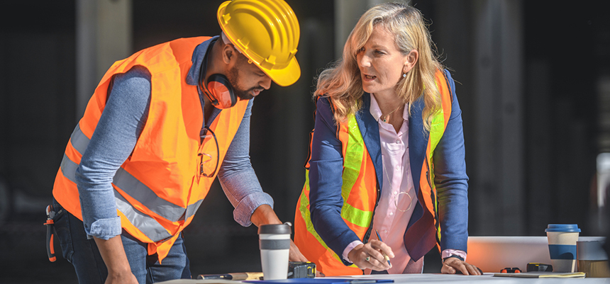 Two people on a construction site putting together a bid