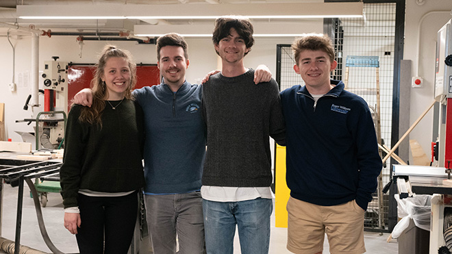 Four students posing for a photo in the Architecture building's wood shop