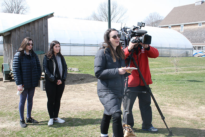 Journalism students observe an alumna reporting the news.