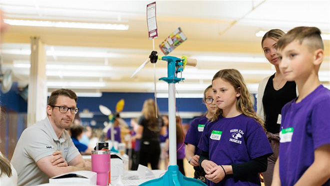 Fourth grade students show their wind turbine to a wind energy expert during KidWind