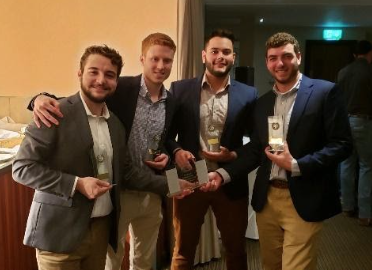 Four team members smile with award 