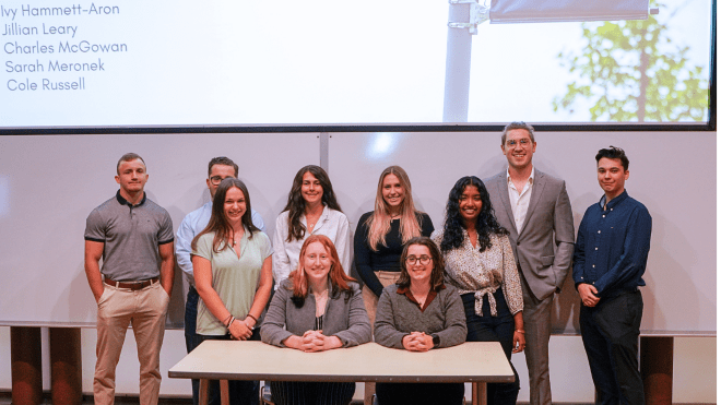 Ten students gathered together smiling after their architecture internship presentations.