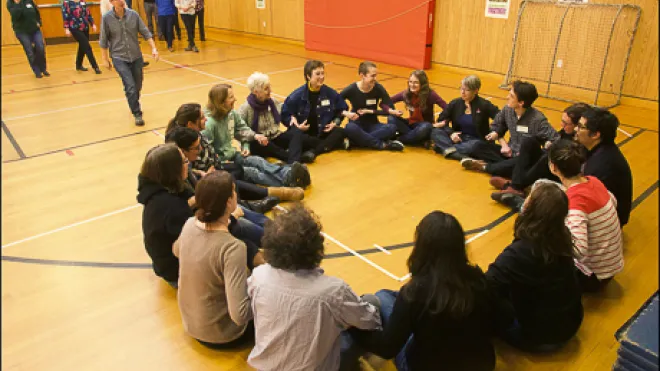 Training participants sit in a circle with linked arms.
