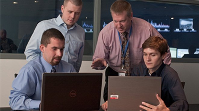 Four people looking at computers.