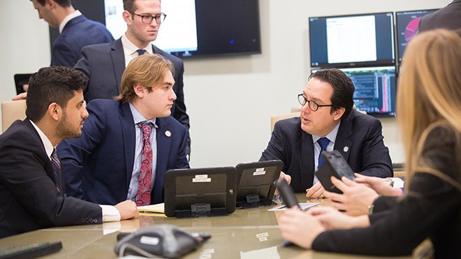 RWU Professor of Finance Michael Melton sits with a group of students in the Center for Advanced Financial Education