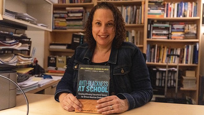 Kerri Ullucci holding a copy of her new book in her office 