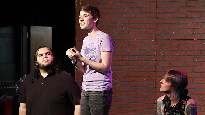 Korbin Johnson, center, with two of their cast mates on a stage 