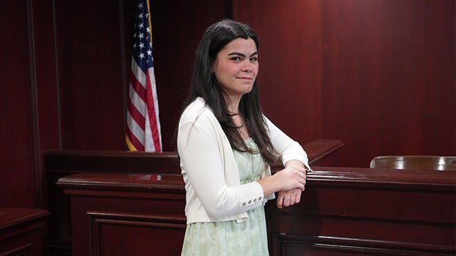 Olivia DaSilva standing in a trial room in RWU's Law School.