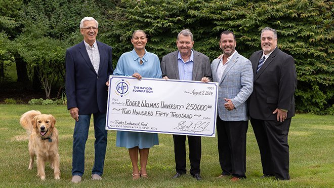 Leaders from RWU and the Hayden Foundation pose with a big check and Roger the dog