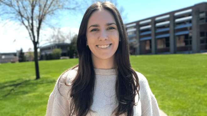 Rachel Borzone in a white sweater with the RWU campus quad in the background