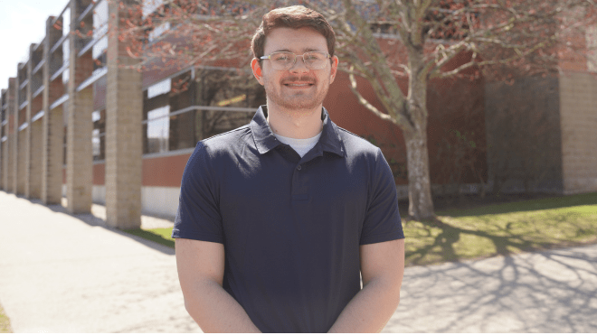 Sam Trieber standing in outside on a sunny day, smiling. 