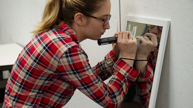 Student writes on a mirror.