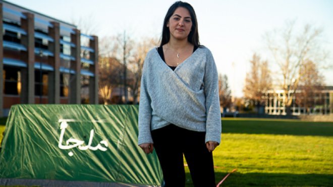 Student stands beside tent.