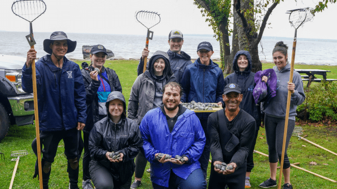 Law students and their quahogging instructor Jody King showing off their 3 dozen quahogs in front of the ocean in which they got them.