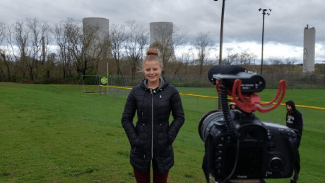 Person standing in grassy field looking at camera. 