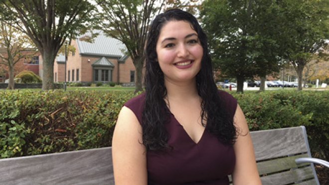 A student sitting on a bench on campus.