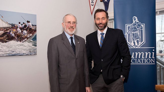 Two men stand near the alumni association banner.