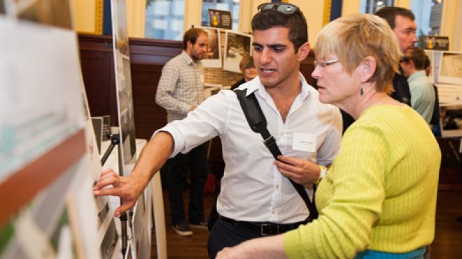 Student explains research poster to a guest