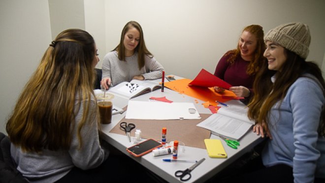 Students work on an art project around a table. 