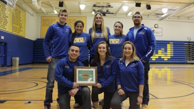 Student athletes and coaches hold their award.