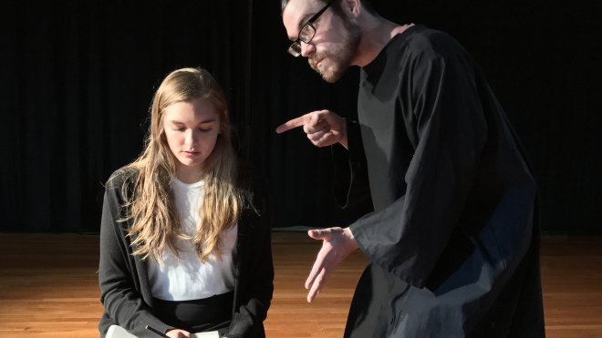 Two actors performa scene on stage.