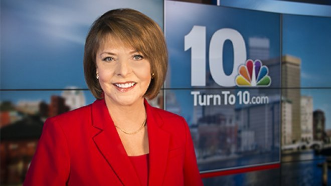 News anchor sitting at the broadcast desk.