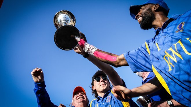 RWU polo team members and coach hold up the championship trophy.