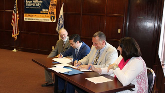 City officials and school administrators sit down to sign an agreement.