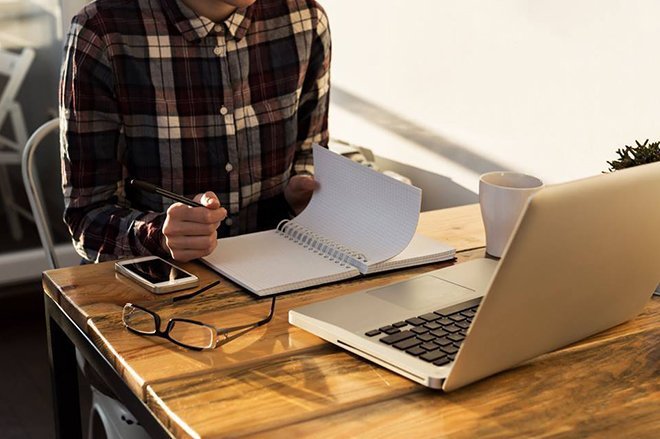 image of UC student in flannel shirt studying with notebook and laptop