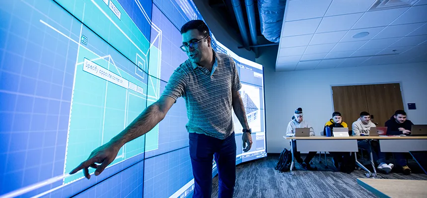 a backlit image of an RWU professor using large scale touch screen while teaching a class on RWU's Bristol campus