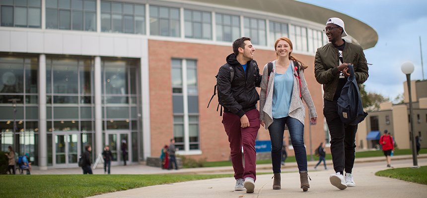 three students walking and smiling outside of GHH