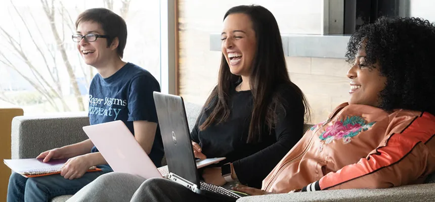 Students sit together with laptops laughing