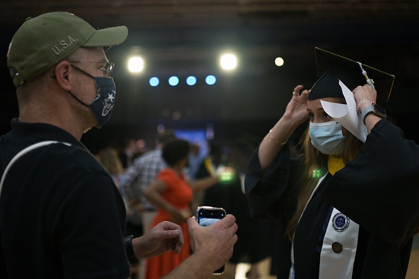 Image of a 2020 graduate adjusting her hat